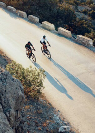 Zwei professionelle Radfahrer fahren mit ihren Rennrädern eine Küstenstraße entlang