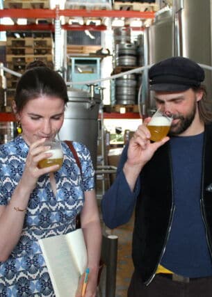 Zwei Personen riechen an gefüllten Biergläsern in einer Brauerei