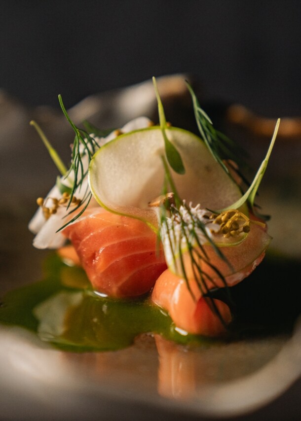 Ein elegant drapiertes Sternegericht mit Lachsforelle auf einem geschwungenen Teller.