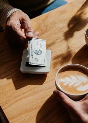 Kontaktlose Zahlung eines Cappuccinos mit einer silbernen Kreditkarte