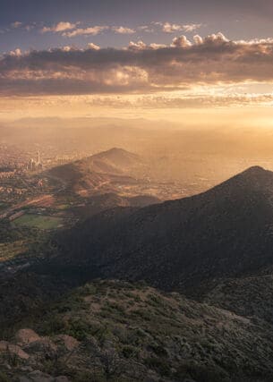 Luftbild von Santiago de Chile mit Sonne hinter Wolken