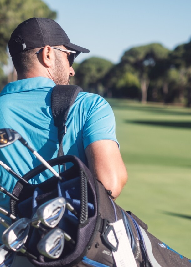 Golfspieler mit Golftasche läuft über einen Golfplatz