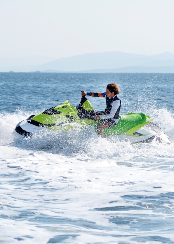 Eine Person fährt mit grünem Jetski auf dem offenen Meer