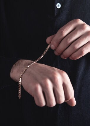 Ein Mann beim Umbinden eines Goldarmbands