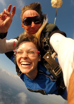 Ein Mann und eine fröhliche Frau beim Tandem-Fallschirmspringen.