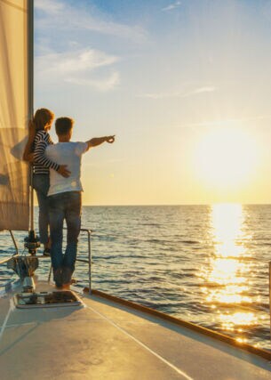 Ein Paar schaut sich auf einem Segelboot den Sonnenuntergang an 