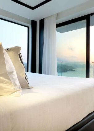 Ein Bett in einem Hotelzimmer mit Blick auf das Meer und den Sonnenuntergang