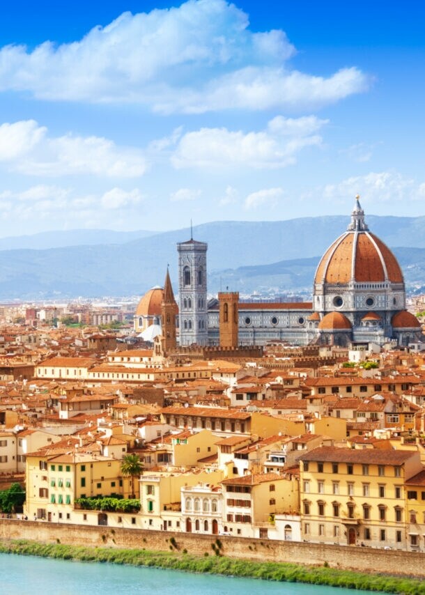 Blick auf eine mediterrane Stadt am Fluss mit historischen Gebäuden und einer Kathedrale