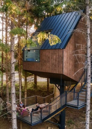 Ein Holzhaus, das zwischen den Baumkronen sitzt