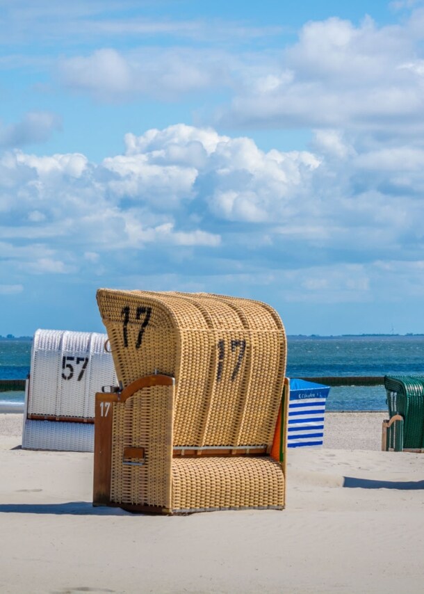 Strandkörbe an einem menschenleeren Sandstrand vor blauem Himmel