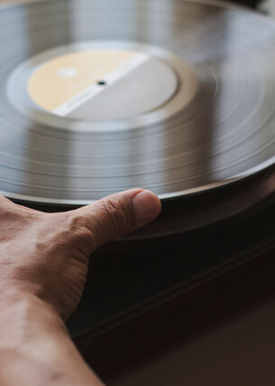Zwei Hände, die das Vinyl auf dem Plattenteller aufnehmen