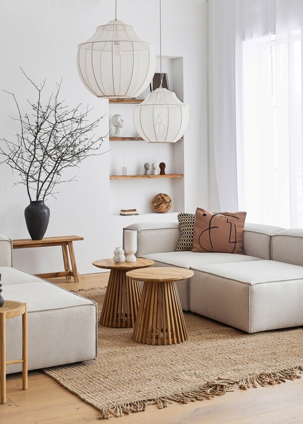 Ein lichtdurchflutetes, modernes Wohnzimmer im skandinavischen Design mit einer kubischen Sitzgruppe aus grauem Stoff und dekorativen Wohnaccessoires