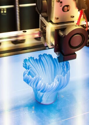 Ein 3D-Drucker druckt ein blaues Objekt aus Plastik