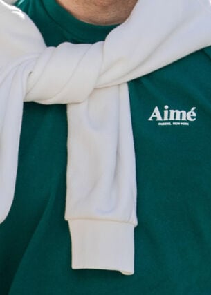 Oberkörper eines sportlichen Mannes in einem grünen T-Shirt mit dem Schriftzug der Marke Aimé
