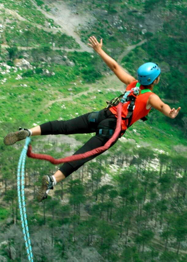 Eine Frau springt von einer Klippe am Bungeeseil in den Abgrund.