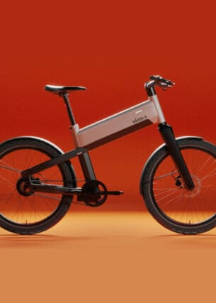 Ein schwarz-silbernes E-Bike der Marke Vässla vor rot-orangenem Hintergrund