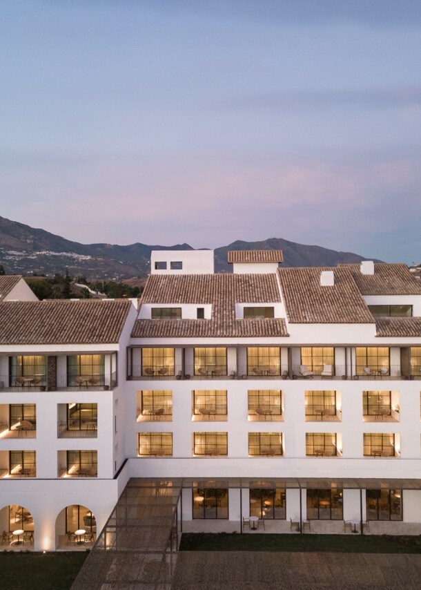 Weißes Hotel am Abend vor einer Bergkulisse