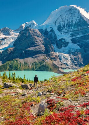 Ein Wanderer steht an einem See im Gebirge eines Nationalparks in Kanada