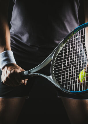 Eine Person hält einen Tennisschläger und Tennisball in der Hand.