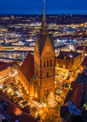 Blick von oben auf eine beleuchtete Stadt bei Nacht mit einer Kirche im Fokus