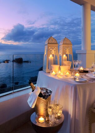 Große Terrasse einer Hotelsuite am Meer mit einem elegant gedeckten Tisch in der Abenddämmerung