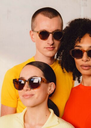 Drei Personen mit einfarbigen Oberteilen und Sonnenbrillen