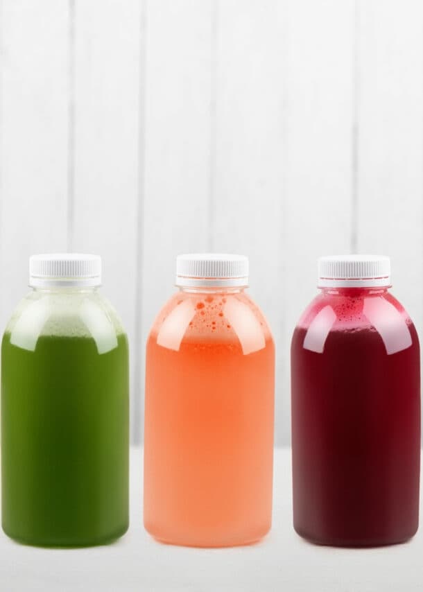Unterschiedlich farbige Fruchtsäfte in Flaschen auf weißem Unter- und Hintergrund