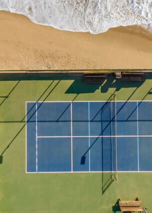 Drohnenansicht des Tennisplatzes am Sand und Meer.