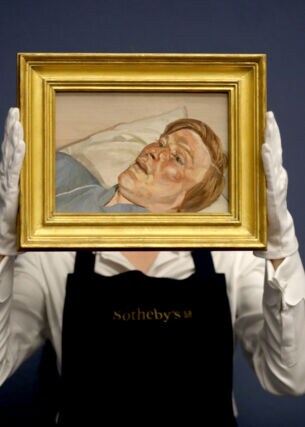 Eine Mitarbeiterin von Sotheby’s hält mit weißen Handschuhen ein kleines Gemälde von Lucian Freud in einem goldenen Rahmen hoch