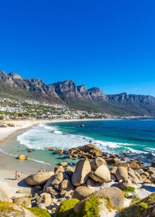 Felsige Strandbucht bei Kapstadt mit Gebirgskette im Hintergrund