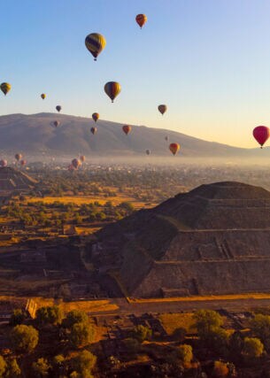 Heißluftballons über Pyramiden auf einer archäologischen Ruinenstätte bei Sonnenaufgang