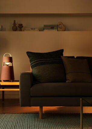 Ein kegelförmiger Bluetooth-Lautsprecher im modernen Design auf einem Tisch neben einer Couch