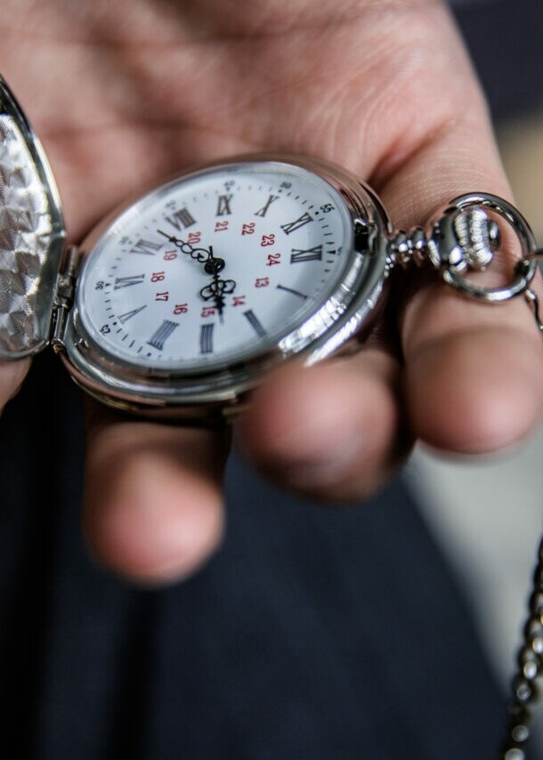 Eine Person hält eine aufgeklappte Taschenuhr in der Hand