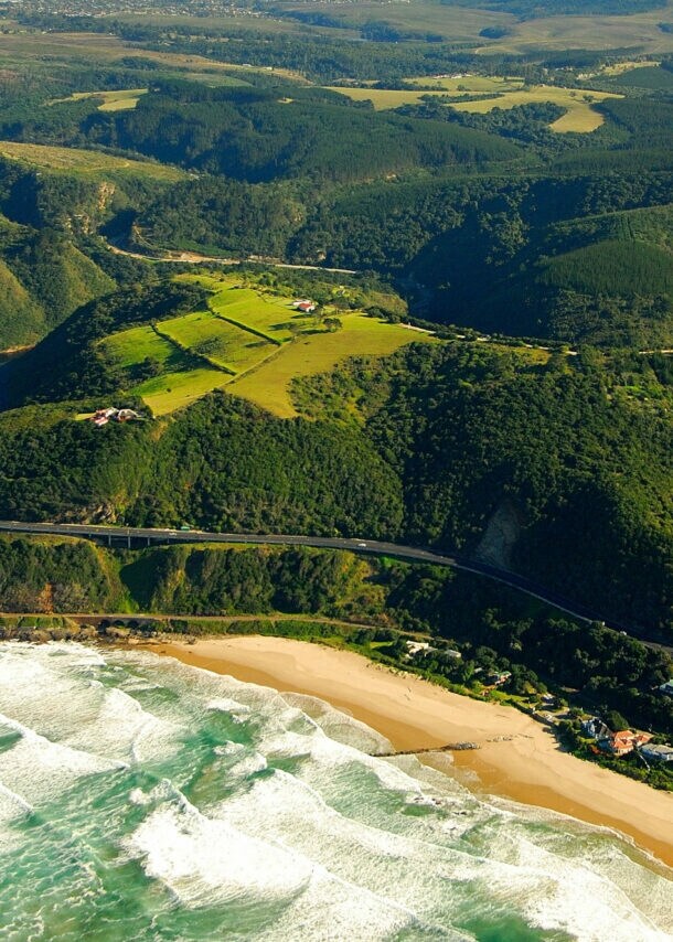 Luftaufnahme der Garden Route, die durch grüne Wälder entlang der Küste führt