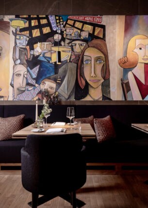 Tische und Bänke mit Kissen in einem Restaurant, an der Wand Malerei