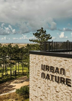 Blick auf die Dachterrasse des Urban Nature Hotels St. Peter Ording, im Hintergrund Bäume, Dünen, Meer und Wolken
