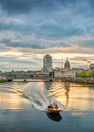 Ein Motorboot fährt auf dem Liffey River in Dublin bei Sonnenuntergang