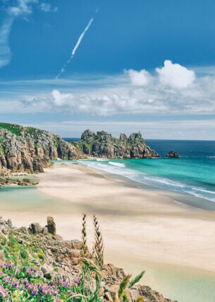 Blick auf die Küste von Cornwall mit Sandstrand, kristallblauem Wasser und Felsvorsprüngen