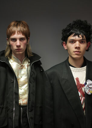 Zwei männliche Models posieren mit schwarzen Jacken und rockigen Stufenhaarschnitten