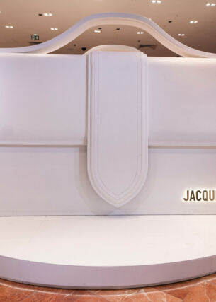 Alt-Text: Eine weiße, überdimensionale Le Bambino-Tasche des Designers Jacquemus in der Pariser Galeries Lafayette.