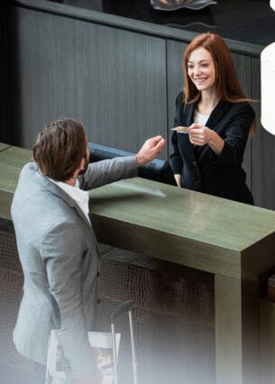 Ein Geschäftsmann hinterlegt eine Kreditkarte bei einer Rezeptionistin beim Einchecken im Hotel