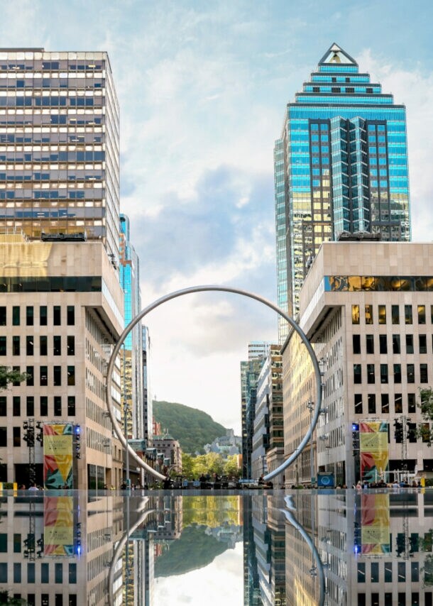 Hochhäuser vor einer Wasserfläche, in der Mitte ein großer Ring