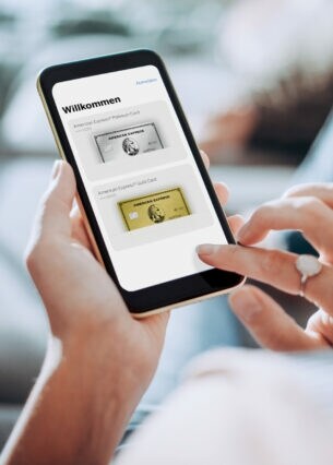 Nahaufnahme eines Smartphones mit der Amex App auf dem Display, in den Händen einer Frau auf einem Sofa