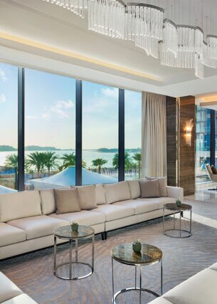Elegantes Hotelfoyer mit hellen Polstermöbeln und bodentiefen Panoramafenstern mit Blick aufs Meer