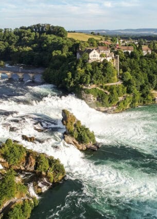 Luftaufnahme des Rheinfalls mit Schloss Laufen inmitten bewaldeter Natur