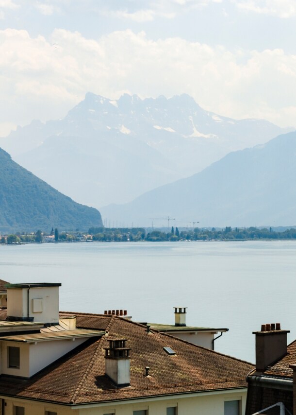 Der Genfer See mit Altbauten im Vordergrund, im Hintergrund die Alpen. 