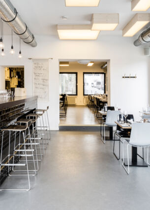 Speiseraum mit Tresen eines modernen Restaurants im industriellen Design und schwarz-weißer Farbgestaltung.