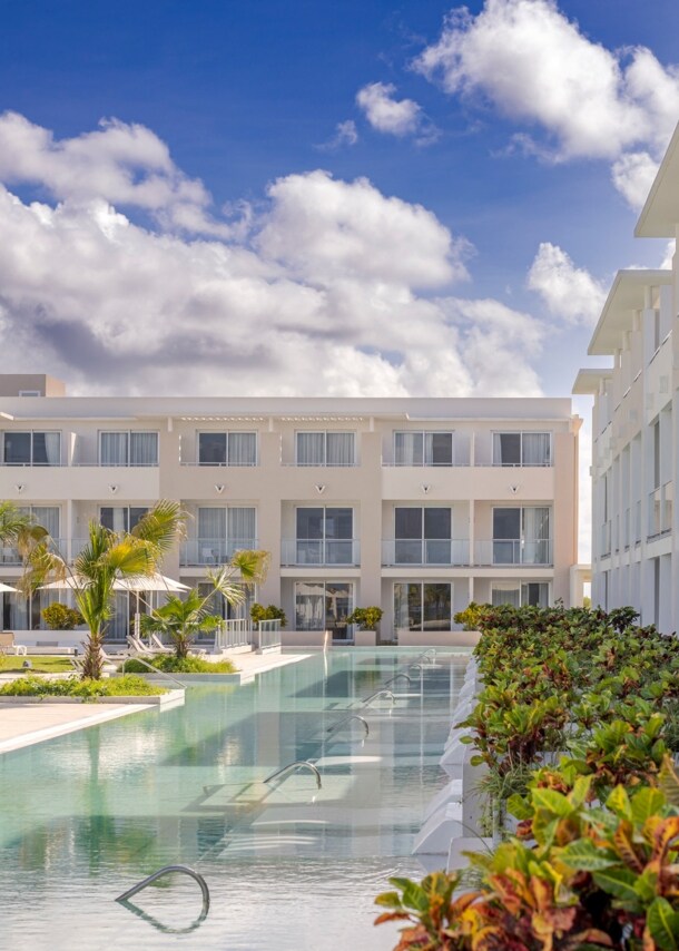 Moderne, dreistöckige Hotelanlage mit begrünter Poollandschaft.