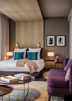 Moderne, helle Hotelsuite mit farbenfrohen Polstermöbeln und Schwarzweißfotografien an den Wänden.