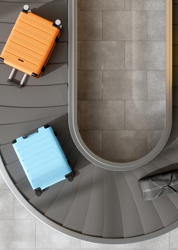 Aufsicht von vier Koffern auf einem Gepäckband.